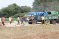 Indian laborers and farmers extracting crop seeds with Thresher Machine in field